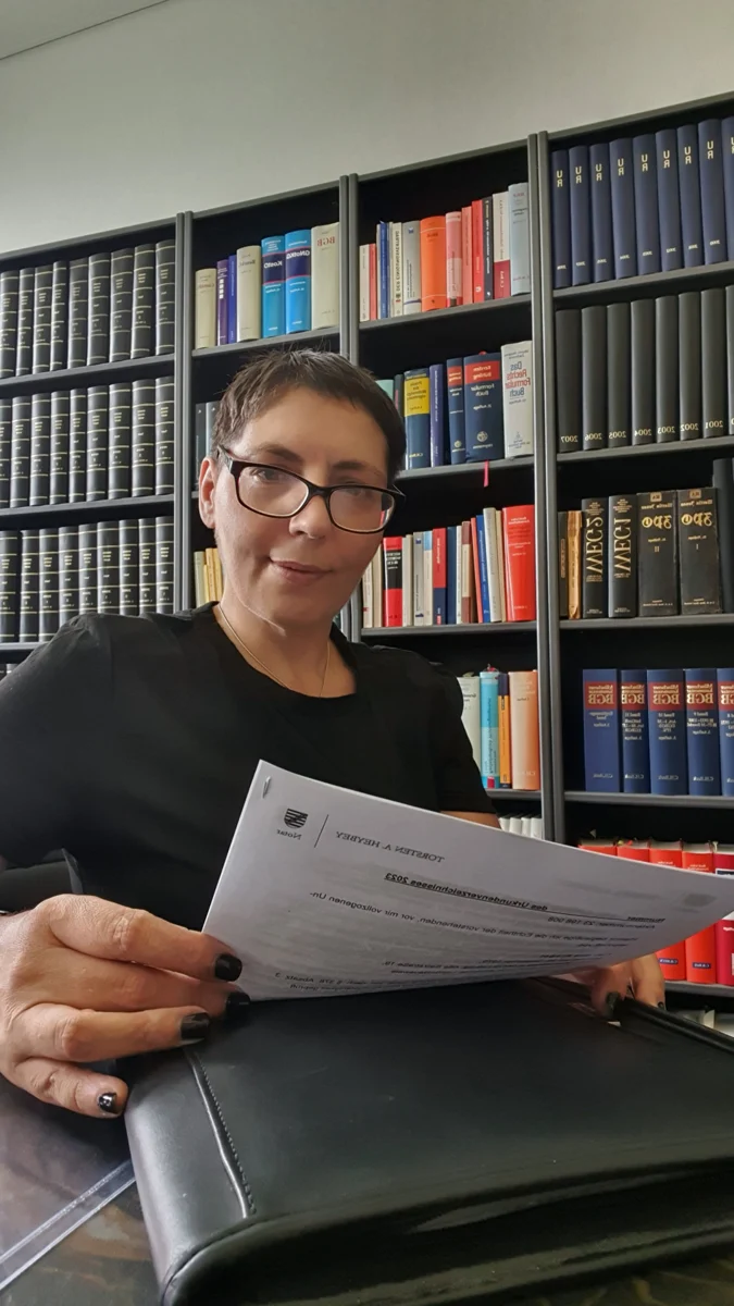 Sina Riegel hält Finanzunterlagen vor einem Bücherregal