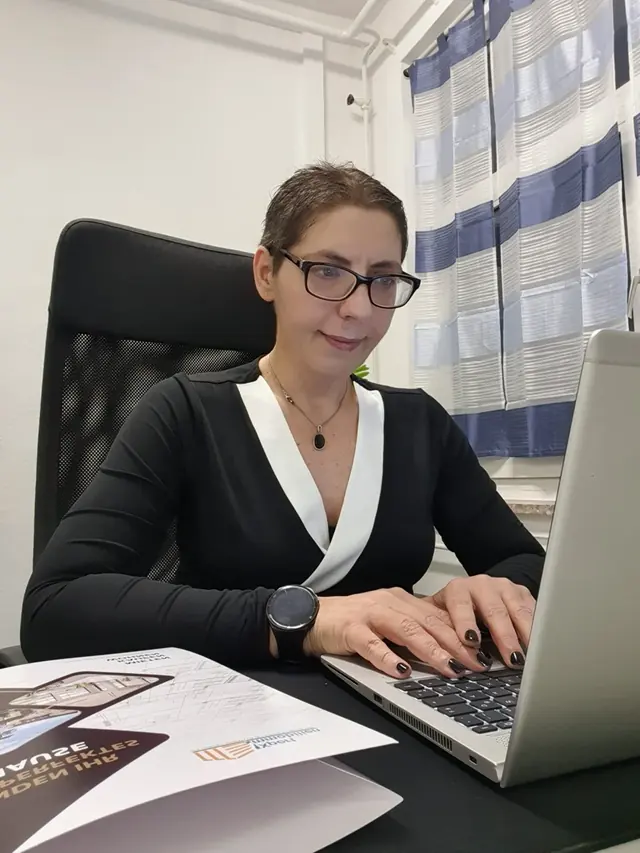 Sina Riegel arbeitet am Laptop mit Unterlagen auf dem Schreibtisch