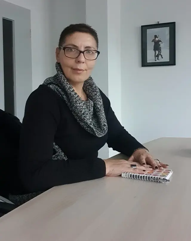 Sina Riegel sitzt mit einem Notizbuch am Besprechungstisch