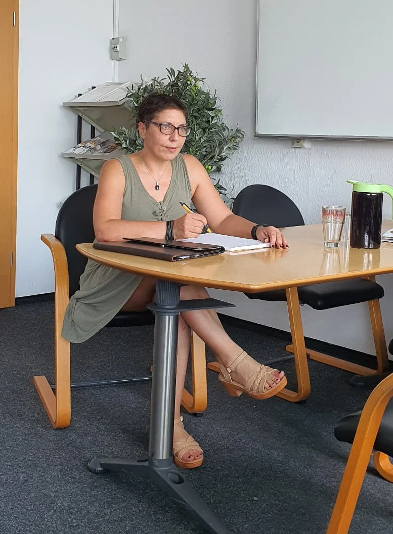 Sina Riegel macht Notizen am Tisch in einem Seminarraum