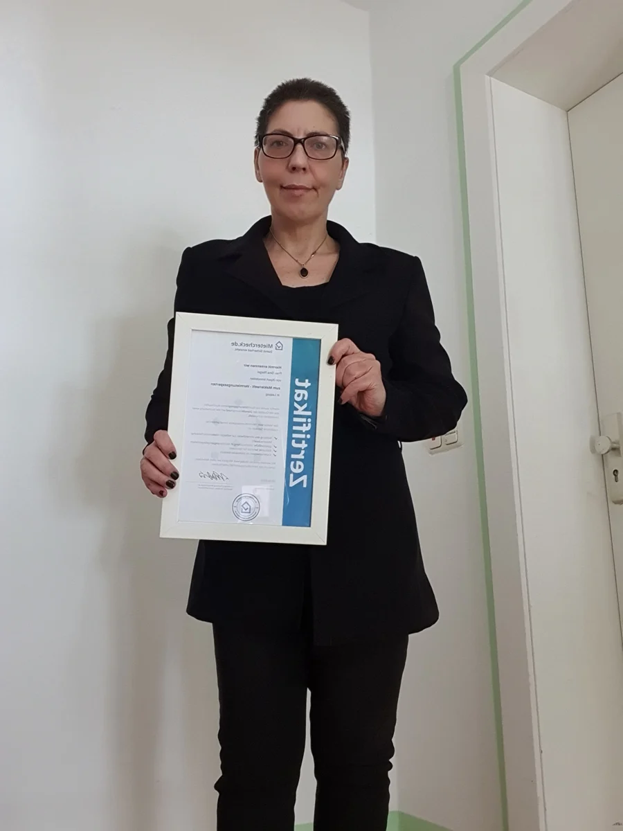 Sina Riegel hält ein gerahmtes Zertifikat in den Händen